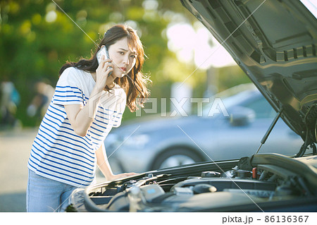 車の故障で電話をする若い女性 車の故障で電話をする若い女性 86136367