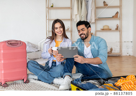 Happy tourists couple using digital tablet and booking travel tickets, choosing destination for next vacation online Happy tourists couple using digital tablet and booking travel tickets, choosing destination for next vacation online 86137805