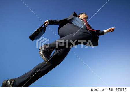 青空を駆けるスーツ姿のビジネスマン 86137855