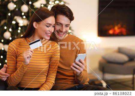Happy couple using smartphone and debit credit card at home Happy couple using smartphone and debit credit card at home 86138022