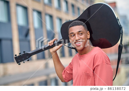 Man with guitar on his shoulder looking to side 86138072