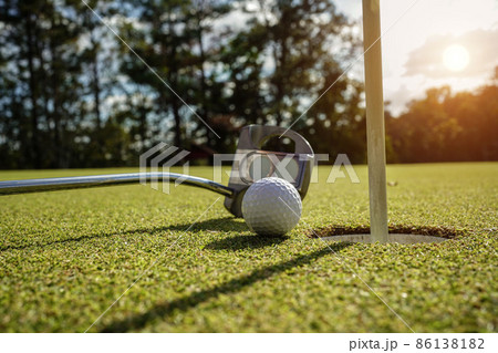 Golf ball and golf club on green in the evening golf course with sunshine in thailand Golf ball and golf club on green in the evening golf course with sunshine in thailand 86138182
