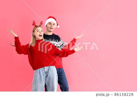 Cute couple in Christmas clothes on pink background Cute couple in Christmas clothes on pink background 86138226