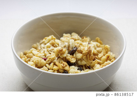 白いボウルに入ったドライフルーツが混ざったグラノーラ 86138517