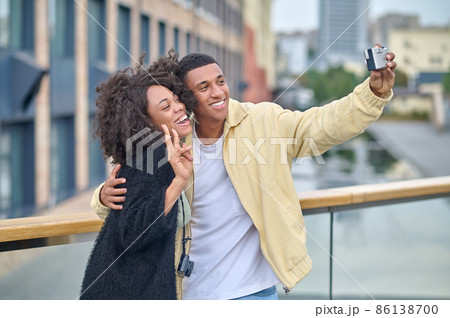 Man taking selfie with woman showing freedom gesture 86138700