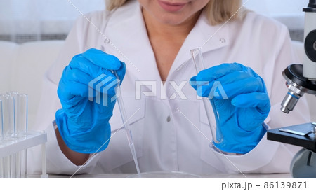 female research chemist scientist in a medical suit and protective gloves conducts research on 86139871