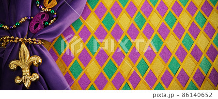 Frame of Mardi Gras Mask and colorful Mardi Gras Beads on diamond shaped background Frame of Mardi Gras Mask and colorful Mardi Gras Beads on diamond shaped background 86140652