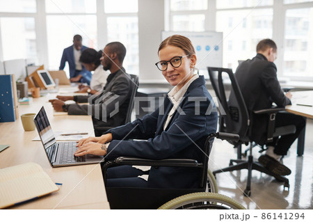 Smiling Woman in Wheelchair Working in Office 86141294