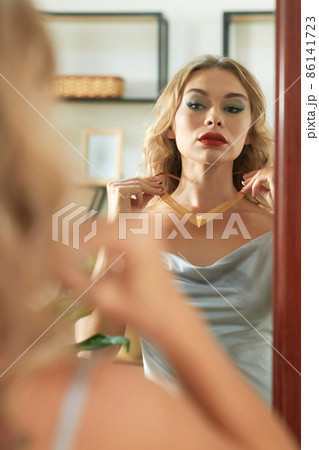 Woman Putting on Golden Necklace Woman Putting on Golden Necklace 86141723