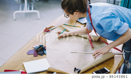 Crop female designer tracing on craft paper in studio Crop female designer tracing on craft paper in studio 86143861