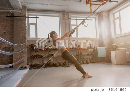 Athletic slender woman holding stretching tape in the gym Athletic slender woman holding stretching tape in the gym 86144662