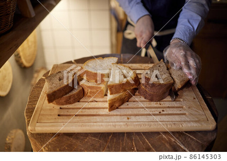 Male hands cutting wheaten bread on the wooden board, selective focus. Male hands cutting wheaten bread on the wooden board, selective focus. 86145303