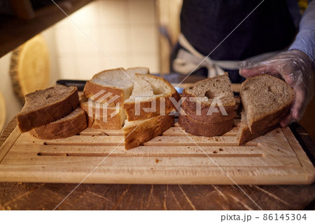 Male hands cutting wheaten bread on the wooden board, selective focus. Male hands cutting wheaten bread on the wooden board, selective focus. 86145304