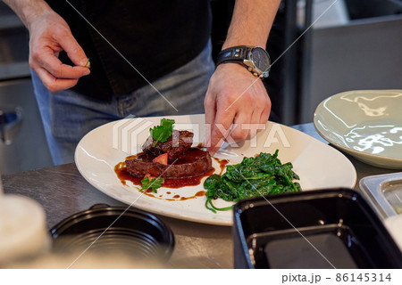 Tenderloin steak wrapped in bacon with red sauce and spinach. Tenderloin steak wrapped in bacon with red sauce and spinach. 86145314