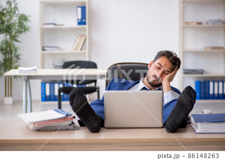 Young male employee extremely tired in the office Young male employee extremely tired in the office 86148263
