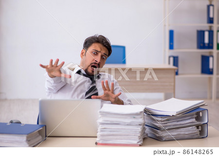 Young male employee and too much work in the office Young male employee and too much work in the office 86148265