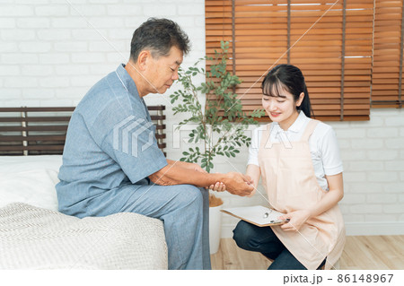 高齢者男性の脈拍を測る女性スタッフ 高齢者男性の脈拍を測る女性スタッフ 86148967
