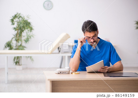 Young male doctor sitting in the clinic Young male doctor sitting in the clinic 86149159