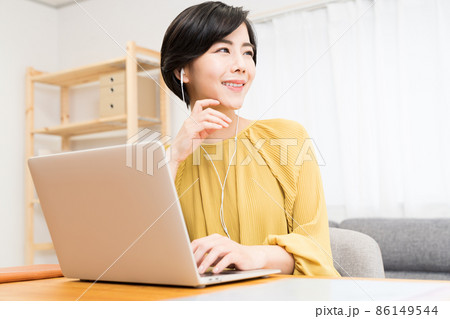 イヤホンをしてパソコンを操作する女性 86149544