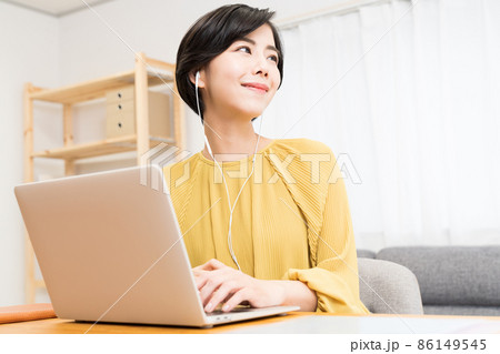 イヤホンをしてパソコンを操作する女性 86149545