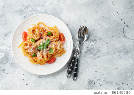 Tasty appetizing classic italian tagliatelle pasta with tomato sauce, cheese parmesan and basil on plate on light table. View from above, horizontal. Top view with copy space Tasty appetizing classic italian tagliatelle pasta with tomato sauce, cheese parmesan and basil on plate on light table. View from above, horizontal. Top view with copy space 86149580