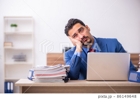 Young male employee unhappy with excessive work at workplace 86149648