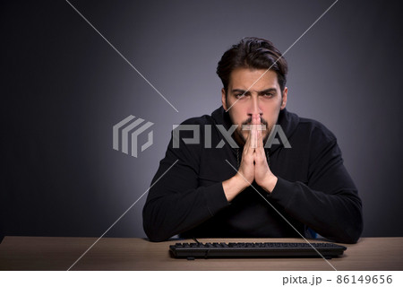 Young male hacker on grey background Young male hacker on grey background 86149656