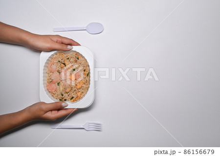 Overhead view woman holding frozen fried rice with shrimp on white background. Overhead view woman holding frozen fried rice with shrimp on white background. 86156679