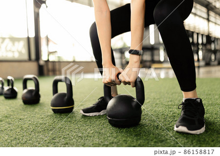exercise concept The black kettlebells being lined on the green carpet for being done kettlebell swing by someone who wears a grey smartwatch and black pair of shoes exercise concept The black kettlebells being lined on the green carpet for being done kettlebell swing by someone who wears a grey smartwatch and black pair of shoes 86158817