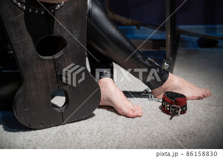 Female hands in wooden shackles during role-playing games. Shameful pillar and leather cuffs for sex. BDSM Domination and punishment. 86158830