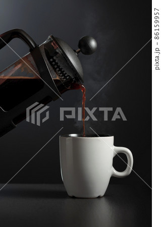 Pouring French press coffee into a cup. Pouring French press coffee into a cup. 86159957