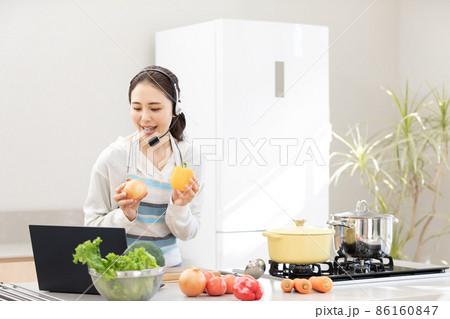 おうち時間 パソコンを使いながら料理をする若い女性 おうち時間 パソコンを使いながら料理をする若い女性 86160847