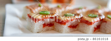 Sushis on plate at japanese restaurant banner panoramic background. Closeup of Aburi Oshi sushi, seared salmon box pressed vinegared rice, Osaka region, Japan travel. Header crop 86161018