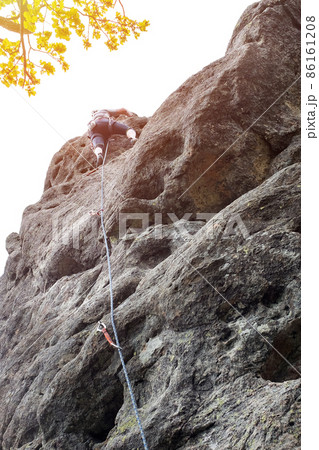 Male climber, young men-climber climbing a difficult route on a cliff. Climber climbs a rocky wall. With safety rope on the rock Male climber, young men-climber climbing a difficult route on a cliff. Climber climbs a rocky wall. With safety rope on the rock 86161208