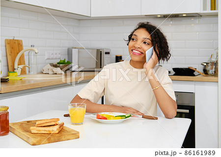 Happy attractive african american woman getting good news at breakfast during phone call Happy attractive african american woman getting good news at breakfast during phone call 86161989