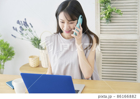 女性 パソコンを見ながら電話する リビング 女性 パソコンを見ながら電話する リビング 86166882