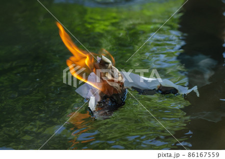 A flaming piece of white paper floats down the river 86167559