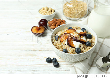 Bowl of oatmeal and ingredients for cooking on white wooden table Bowl of oatmeal and ingredients for cooking on white wooden table 86168115