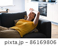 Young millenial woman lying on the couch tired with headache. 86169806