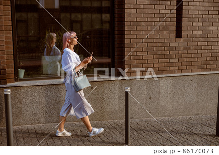Young woman walking on the street and listening to music Young woman walking on the street and listening to music 86170073