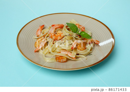 Plate of tasty shrimp pasta on blue background 86171433