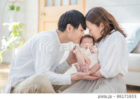 赤ちゃんにキスする若いパパと笑顔のママのポートレート 赤ちゃんにキスする若いパパと笑顔のママのポートレート 86171653