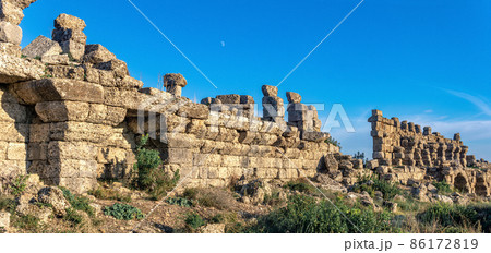 ruins of ancient city walls against the backdrop of the sky with moon in Side, Turkey 86172819