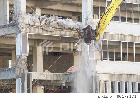 老朽化した公共建造物の解体作業をする重機 86173171