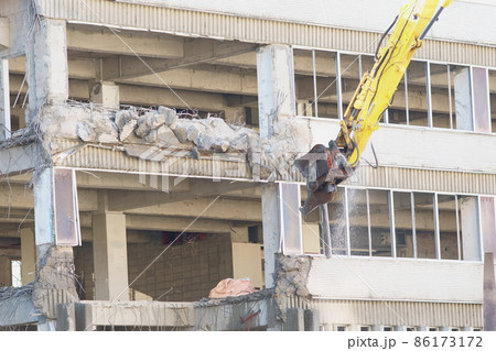 老朽化した公共建造物の解体作業をする重機 86173172