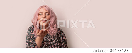 Portrait of pretty woman looking at camera and gives an air kiss isolated light pink background, people lifestyle concepts Portrait of pretty woman looking at camera and gives an air kiss isolated light pink background, people lifestyle concepts 86173523