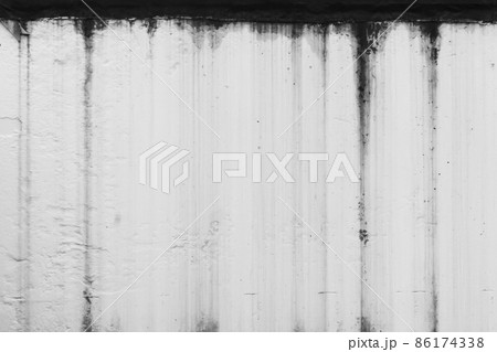 Black dirty spots of fuel oil flow liquid down the white old wall surface chemical industry background 86174338