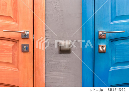 Orange and blue wooden door with iron handle and light switch next to part or element of the interior in the toilet 86174342