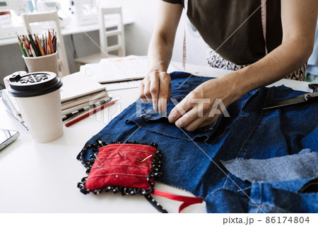 Mending Clothes, how to mend old Clothes. Sustainable fashion, Denim Upcycling Ideas, Using Old Jeans, Repurposing, Reusing Old Jeans, Upcycle Stuff. Woman seamstress cut and repair old blue jeans 86174804