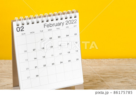 February 2022 desk calendar on wooden table with yellow background. February 2022 desk calendar on wooden table with yellow background. 86175785
